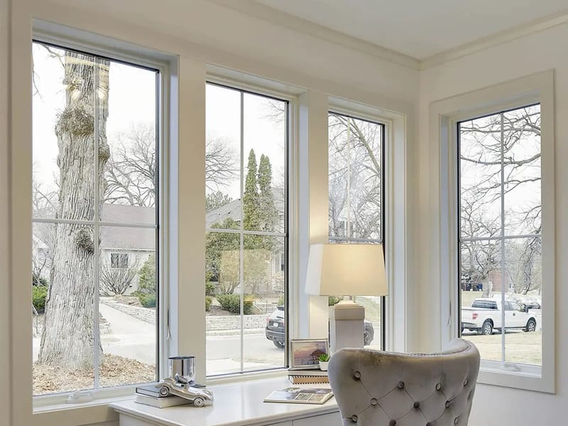 A bank of windows wrapping a corner above a desk, filling the room with daylight