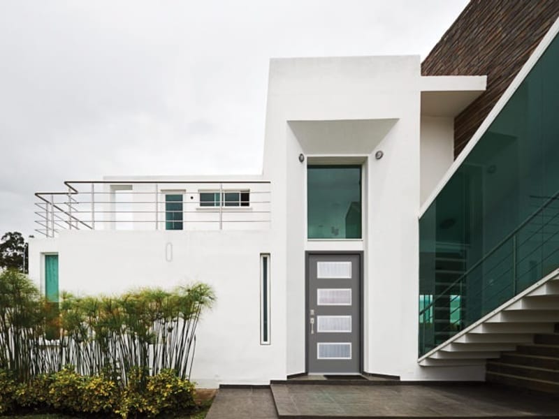 A grey contemporary entry door with narrow vertical glazing in a white render facade