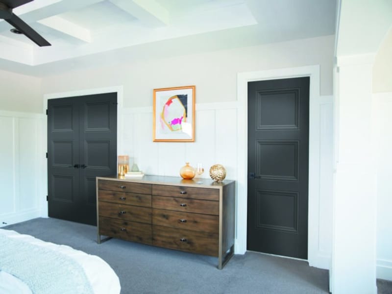 Two dark grey two-panel interior doors either side of a timber dresser