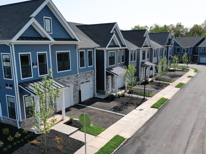 A row of townhomes with black-framed windows across blue and grey siding