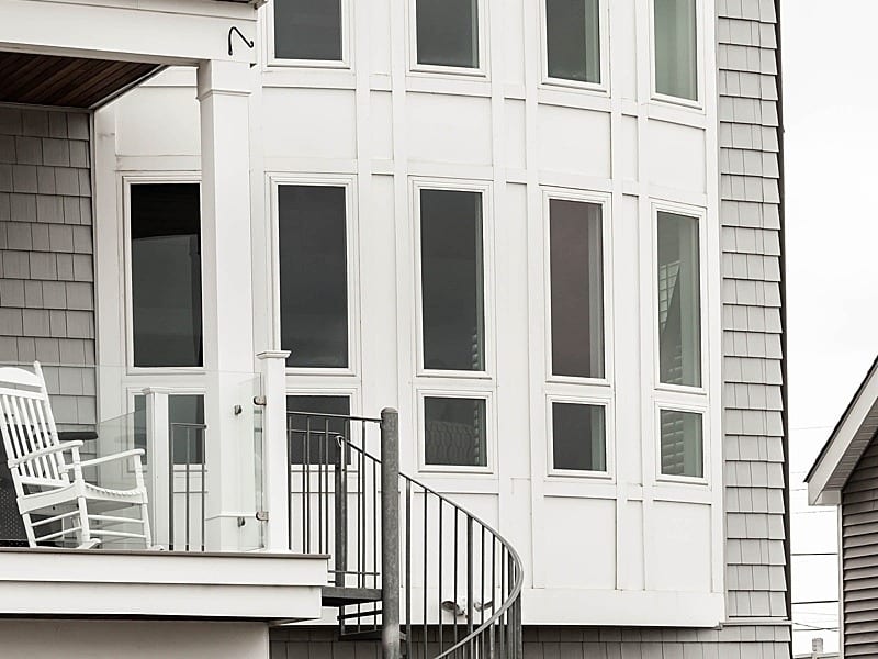 A two-storey bowed window bay in a white shingled facade